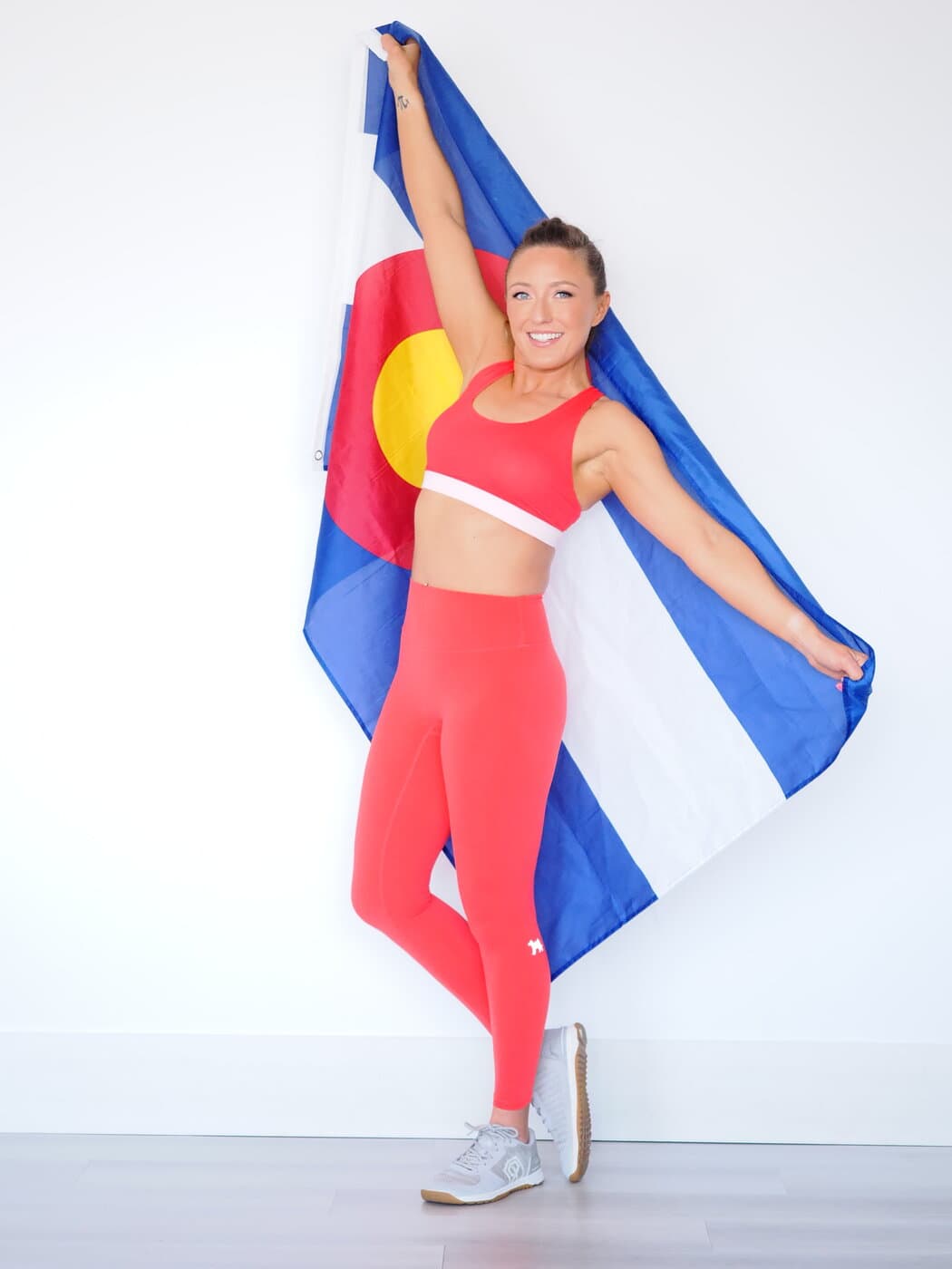 Aubrielle Brennan holding the Colorado flag overhead — strong, proud, and home-grown